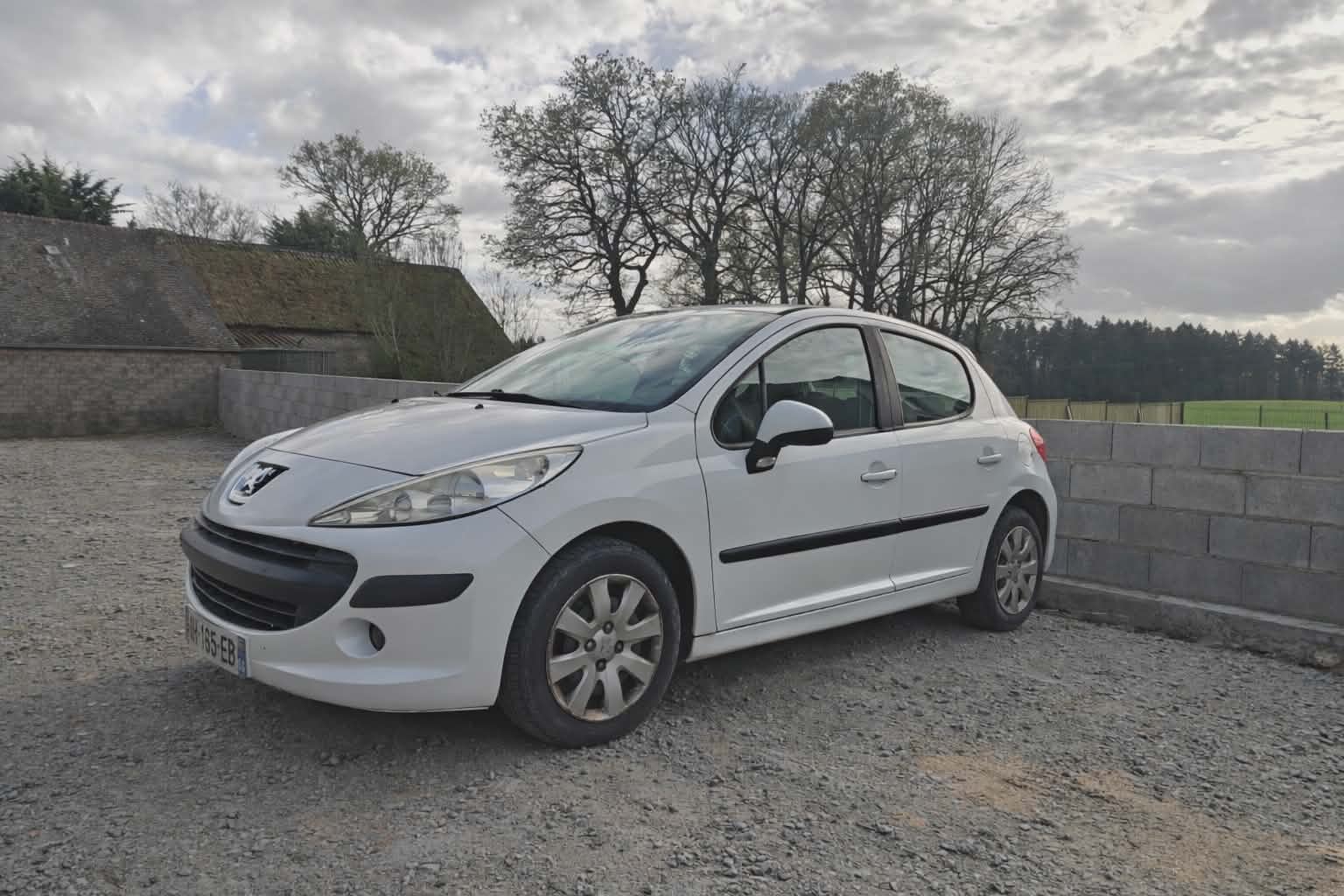 Voiture Peugeot 207 blanche en attente de location au garage